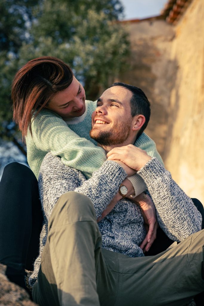 Couple assis en extérieur, moment tendre et spontané, lumière douce.