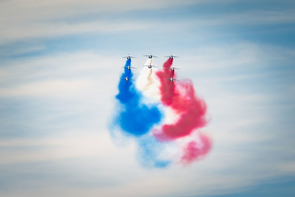 Aviation acrobatique avec fumigènes colorés en ciel bleu.