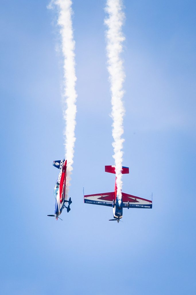 Avions réalisant une figure acrobatique avec traînées de fumée.