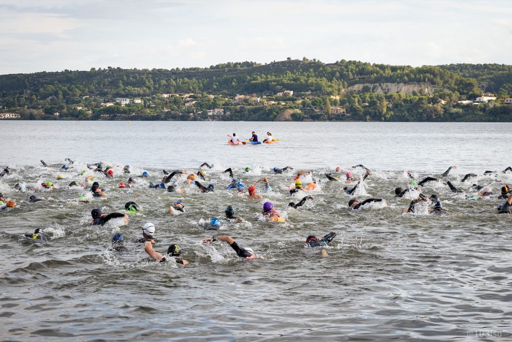 Groupe de nageurs en eau libre lors d’une compétition en extérieur.