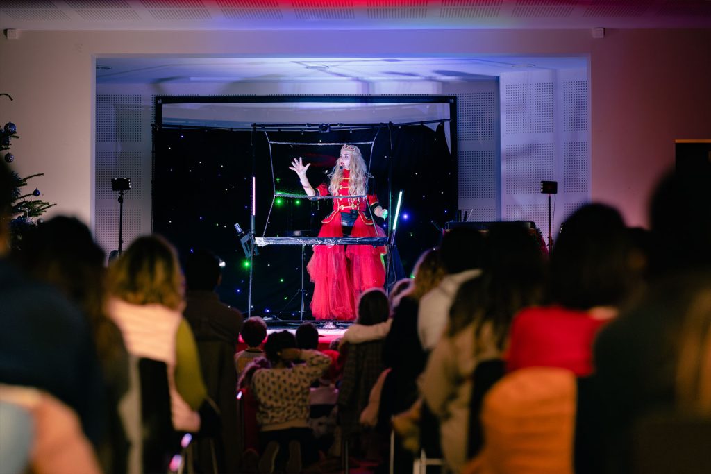 Chanteuse sur scène en robe rouge devant un public lors d’un concert en intérieur.