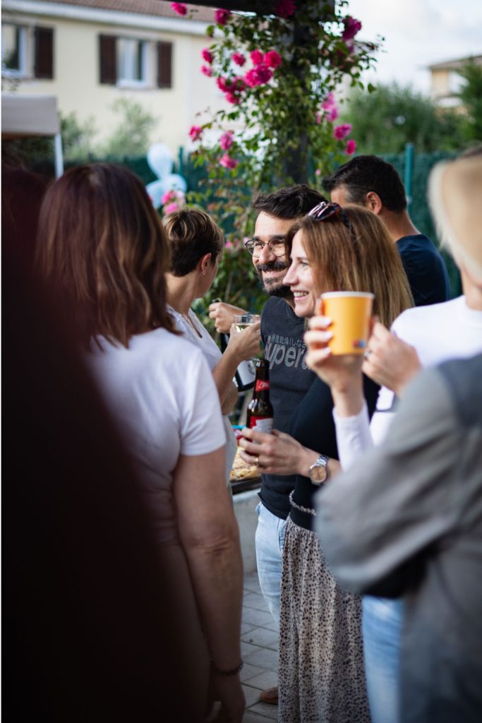 Groupe de personnes discutant lors d’un événement convivial en extérieur.