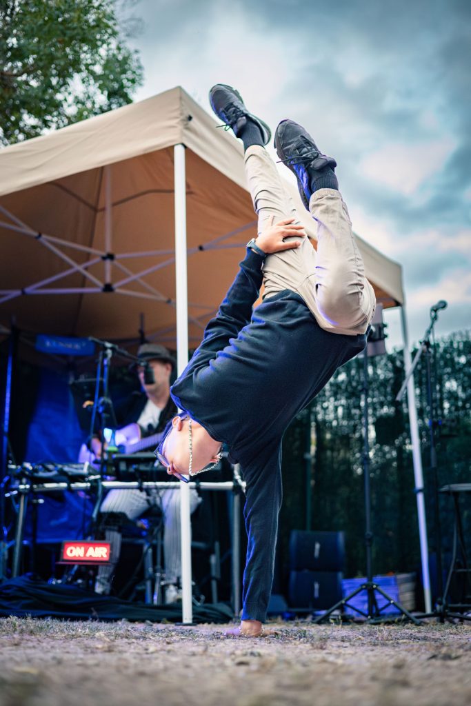 Danseur réalisant une figure acrobatique en extérieur lors d’un événement avec musique live.