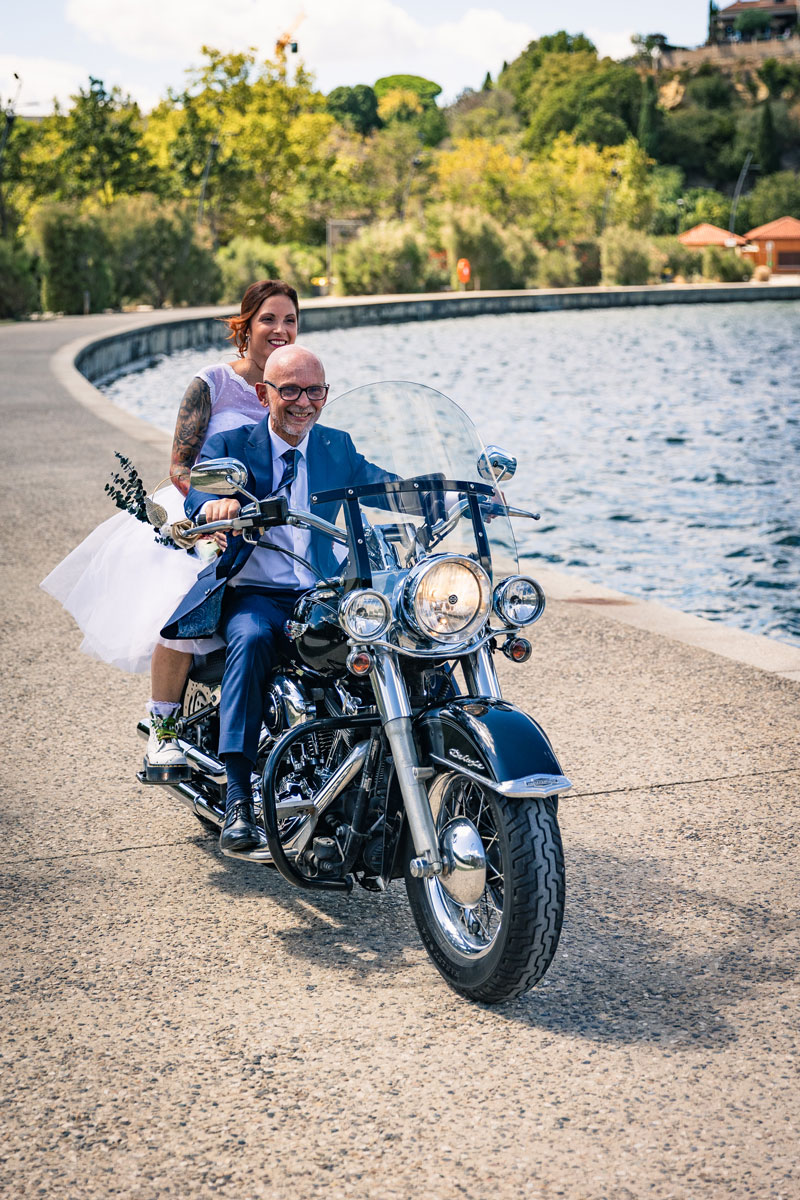 le papa et la mariée roulant à moto au bord de l’eau, moment spontané et joyeux lors de leur journée de mariage.