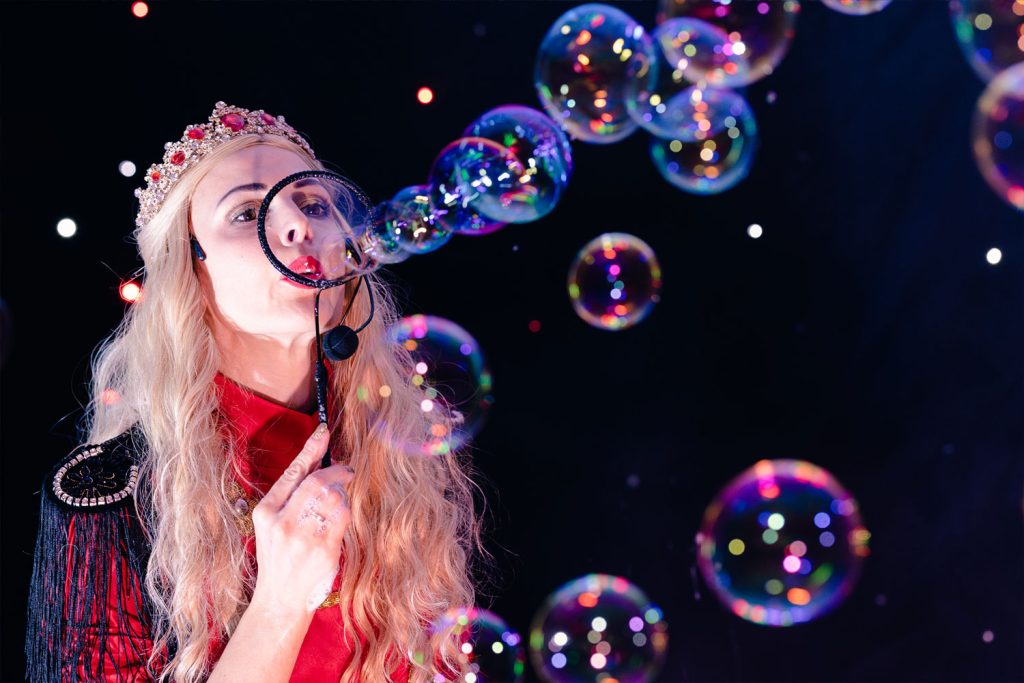 Artiste sur scène créant des bulles lumineuses lors d’un spectacle.