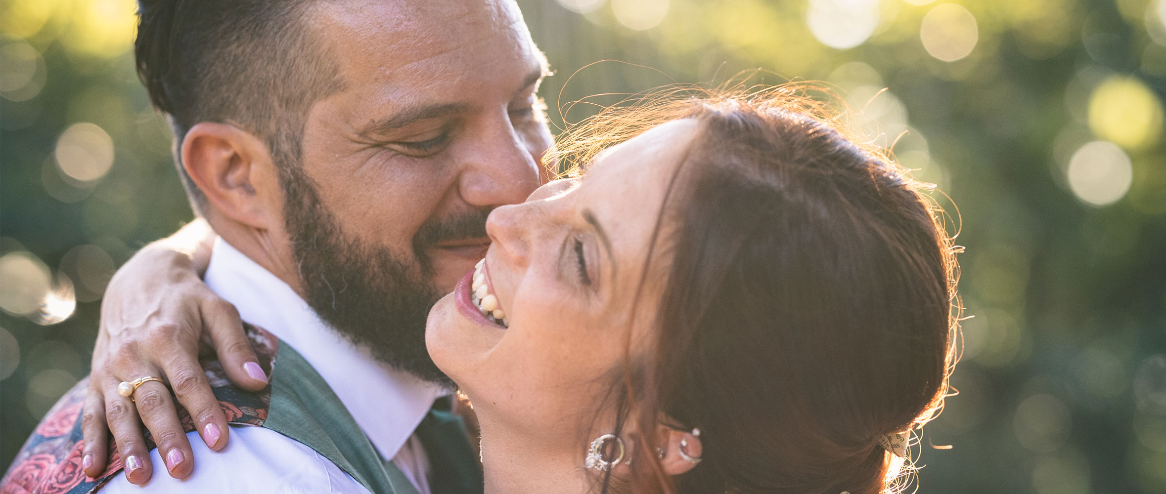 Couple de mariés s’enlaçant en extérieur au coucher du soleil, moment tendre et spontané, lumière naturelle.