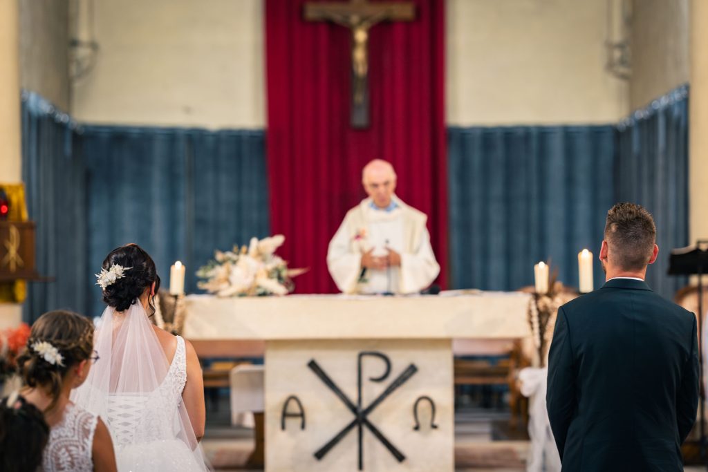 Cérémonie religieuse devant l’autel, mariés de dos.