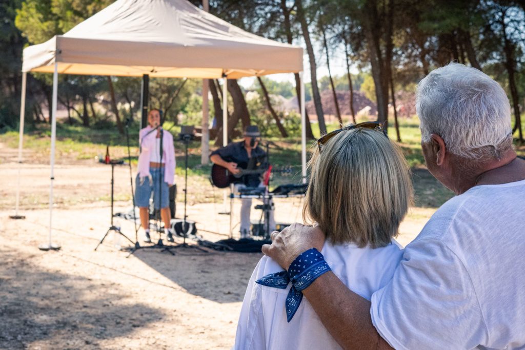 Couple regardant un concert en extérieur, ambiance détendue sous un chapiteau.