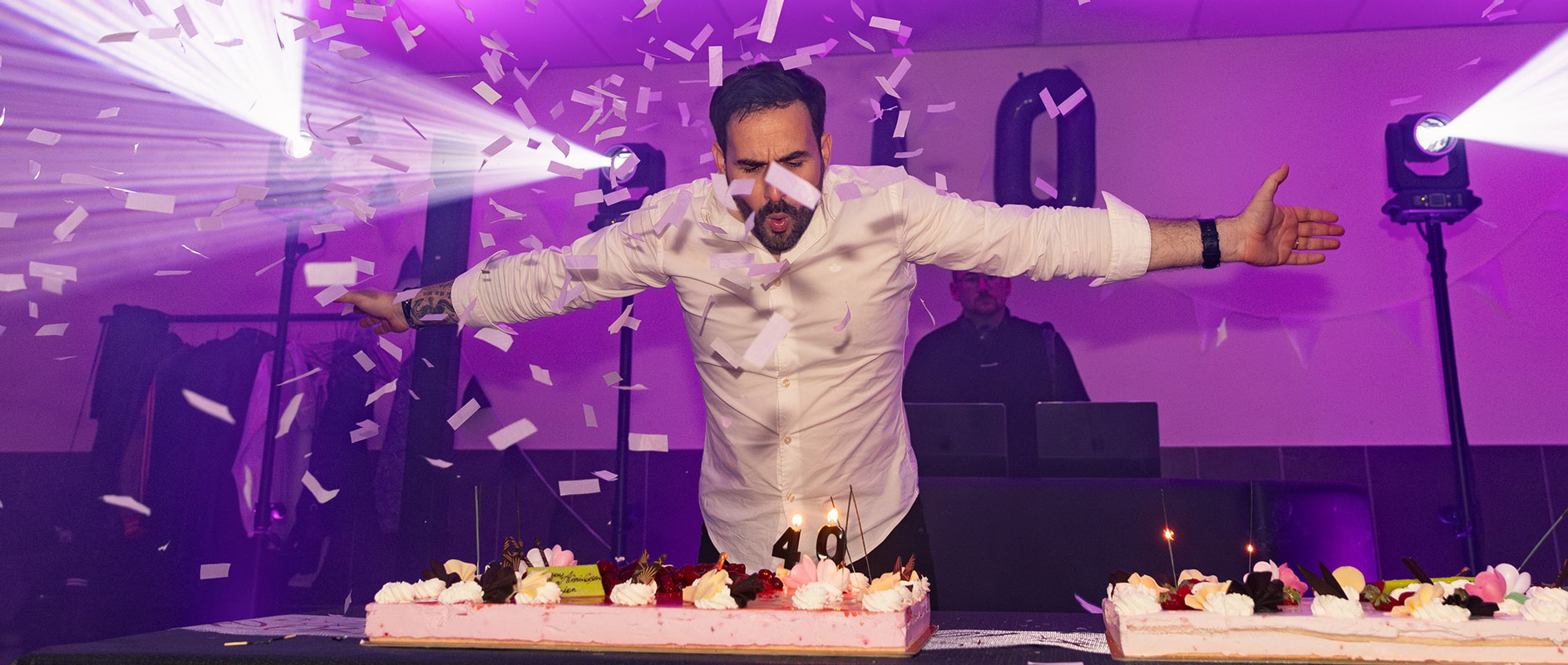 Célébration en intérieur avec confettis, lumière colorée et gâteau d’anniversaire, ambiance festive et joyeuse.