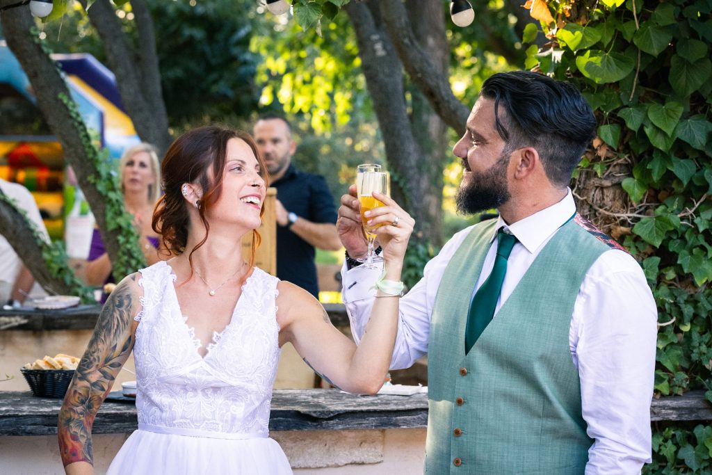 Les mariés trinquent en extérieur, moment convivial et spontané.