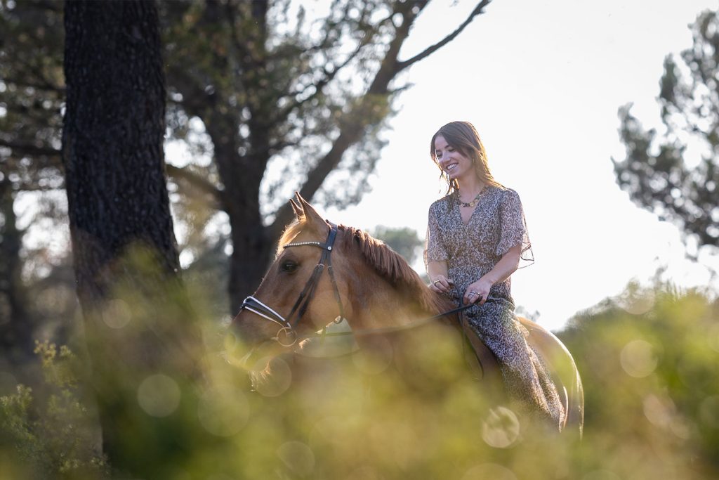 Personne montant un cheval en extérieur, ambiance nature, lumière douce.