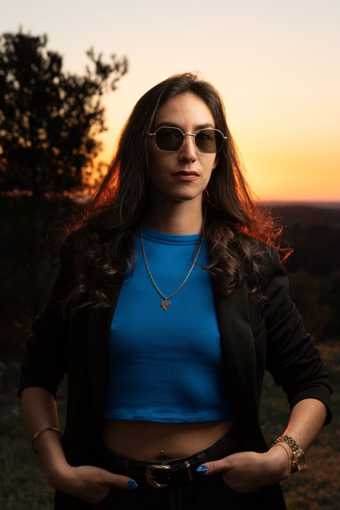 Portrait en extérieur au coucher du soleil, modèle debout, éclairage chaud et naturel.