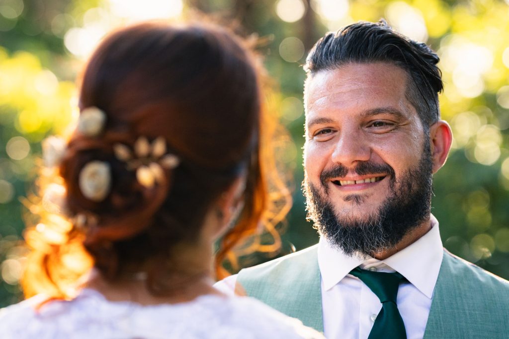Portrait du marié souriant en extérieur, lumière naturelle dorée.