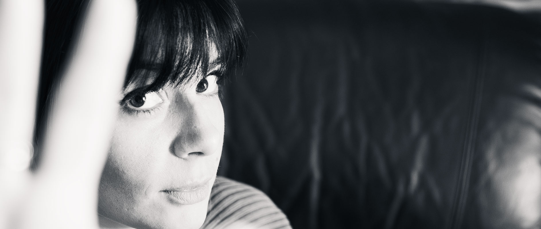 Portrait en noir et blanc avec regard direct et main floue au premier plan, ambiance intime et artistique.